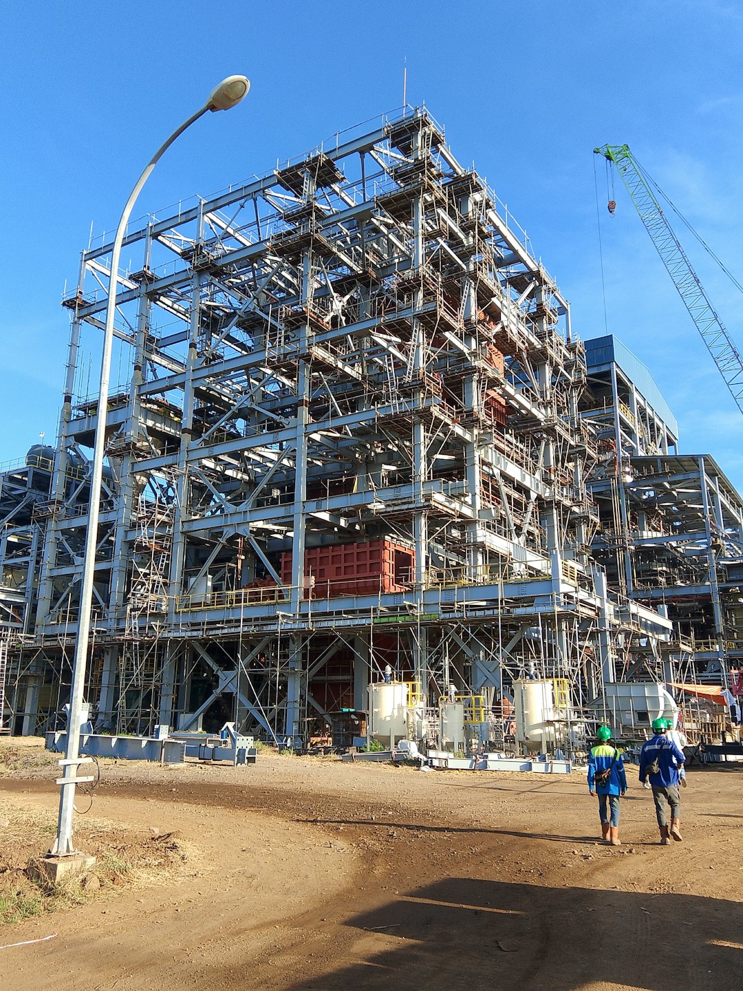 Construction workers walk toward a steel building framework under construction.